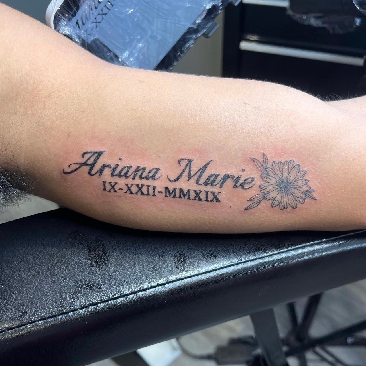 Read: Typography with Child's Name, Roman Number Birthday, and Flower Arm Tattoo